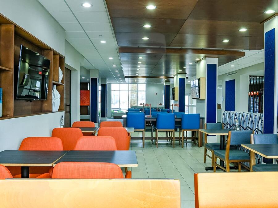 A modern restaurant with multiple seating areas, including tables and booths, and a variety of chairs.