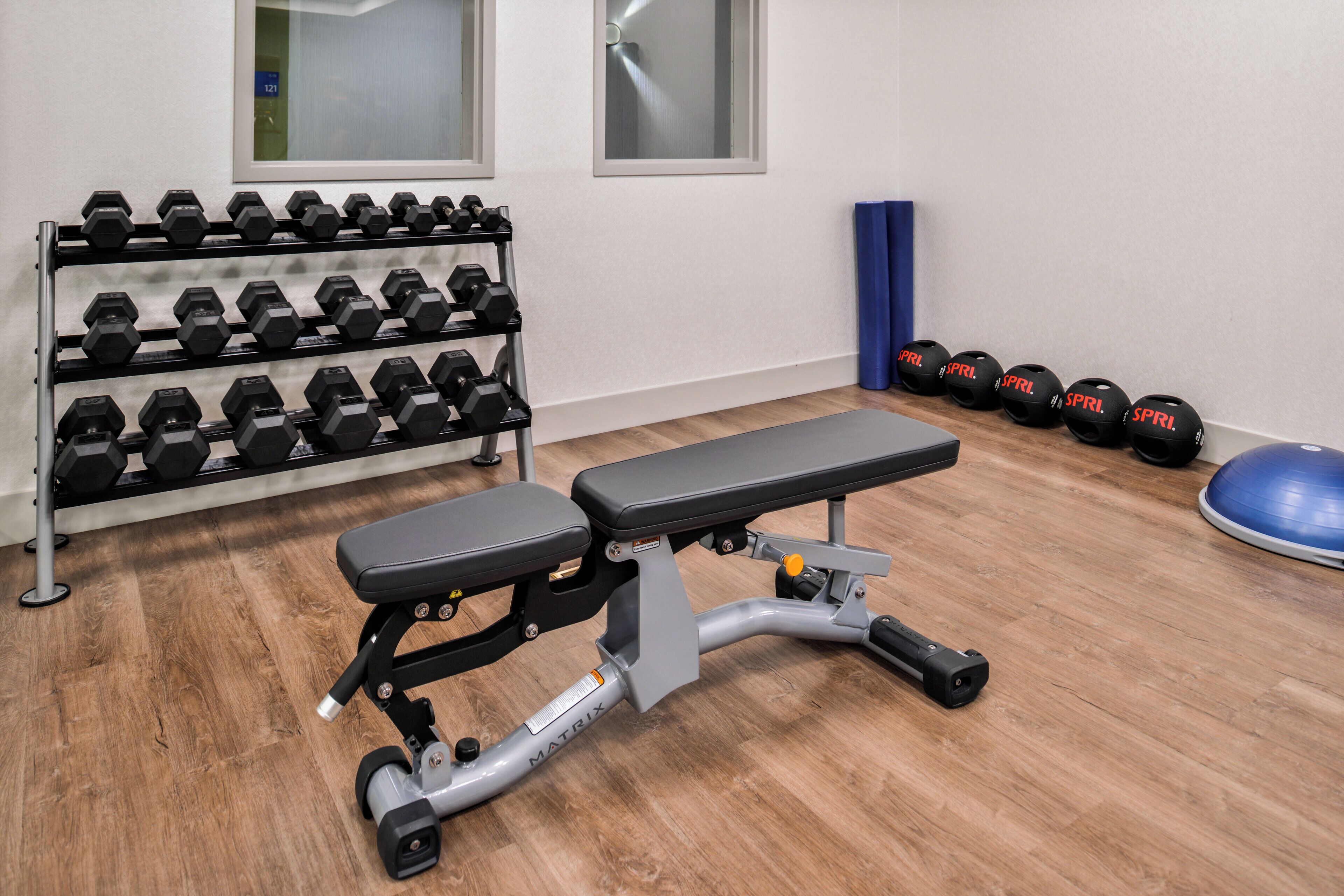 Un gimnasio con banco, mancuernas y pelotas de ejercicio.