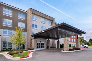 A multi-story hotel with a covered entrance, stone facade, and a parking lot. - Holiday Inn Express & Suites Siloam Springs by IHG (Siloam Springs)