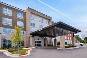 A multi-story hotel with a covered entrance, stone facade, and a parking lot.