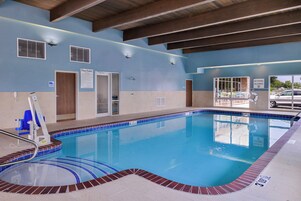 A swimming pool with a lifeguard chair, pool rules sign, and a no diving allowed sign.