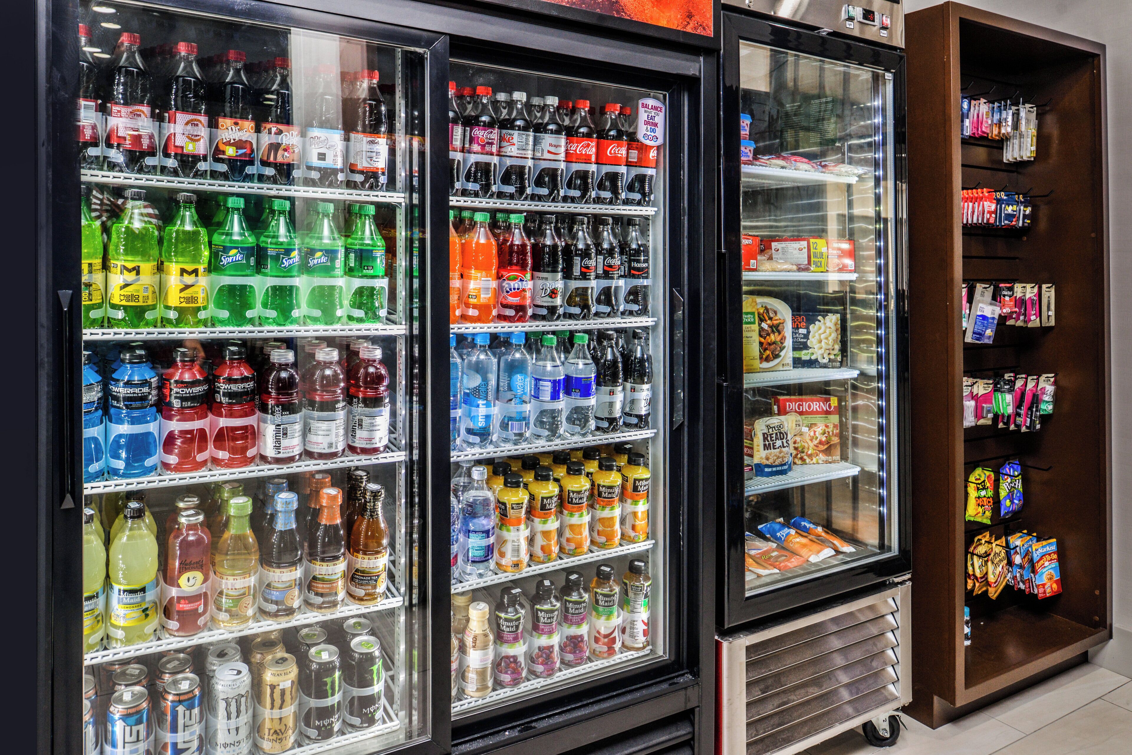 Un refrigerador para bebidas repleto de varias opciones y una alacena con aperitivos a la derecha.