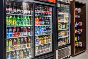 A beverage refrigerator stocked with various drinks and a snack shelf to the right. - Holiday Inn Express & Suites Siloam Springs by IHG (Siloam Springs)