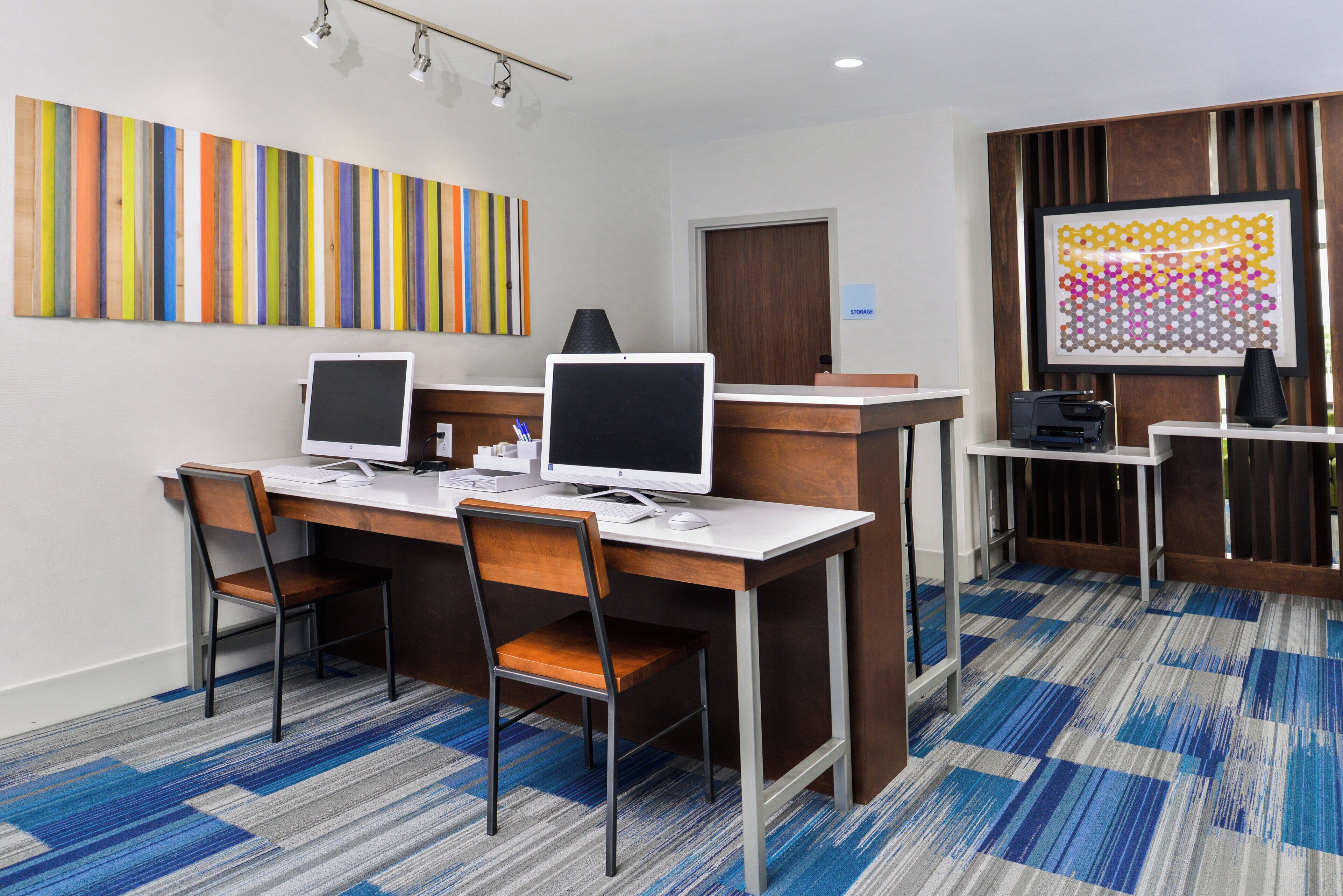 A conference room with two desktop computers, a whiteboard, and a storage area.