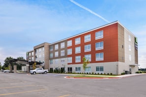 A Holiday Inn Express hotel with a modern design, featuring a red and beige facade, multiple windows, and a parking lot with a 'No Parking' sign. - Holiday Inn Express & Suites Siloam Springs by IHG (Siloam Springs)