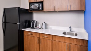 A compact kitchen with a black refrigerator, a microwave, a coffee maker, and a sink. - Holiday Inn Express & Suites Siloam Springs by IHG (Siloam Springs)