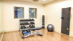 A home gym with a bench, dumbbells, a medicine ball, and resistance bands. - Holiday Inn Express & Suites Siloam Springs by IHG (Siloam Springs)
