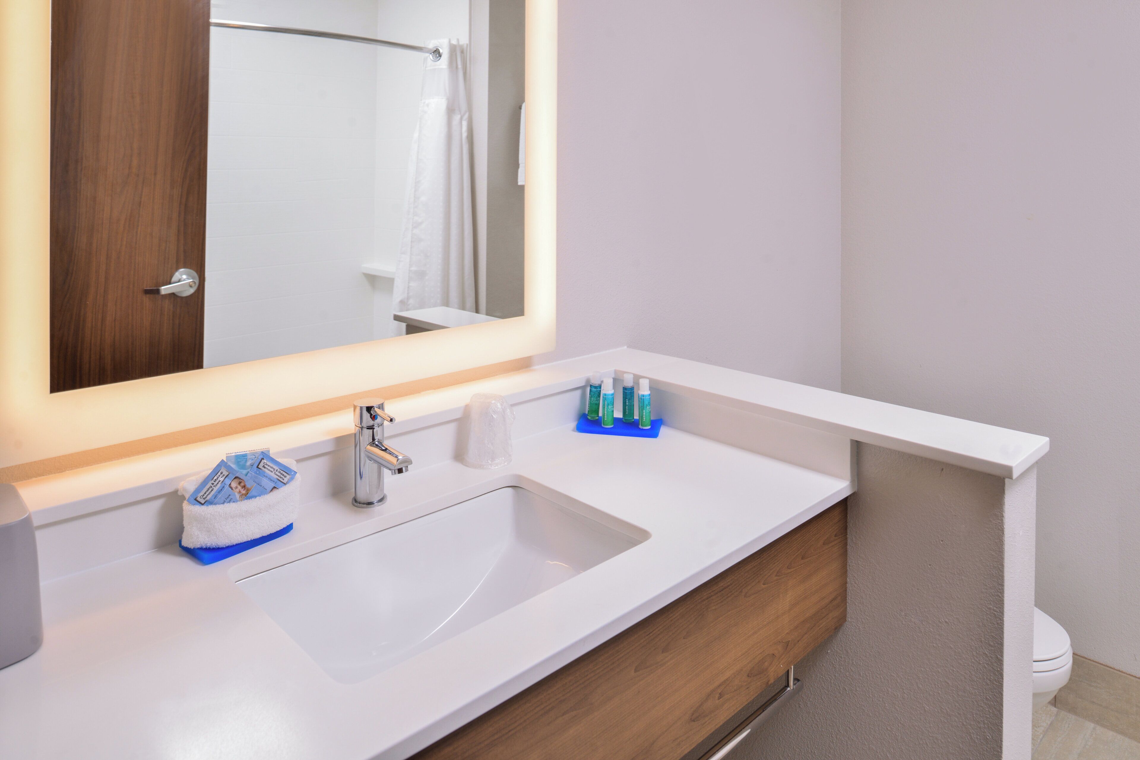 A bathroom with a white sink, a mirror, and toiletries.