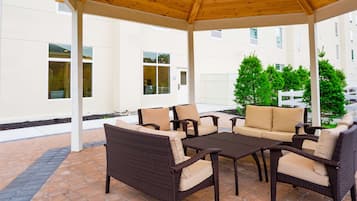 Un patio al aire libre con mobiliario de mimbre y techo de madera.