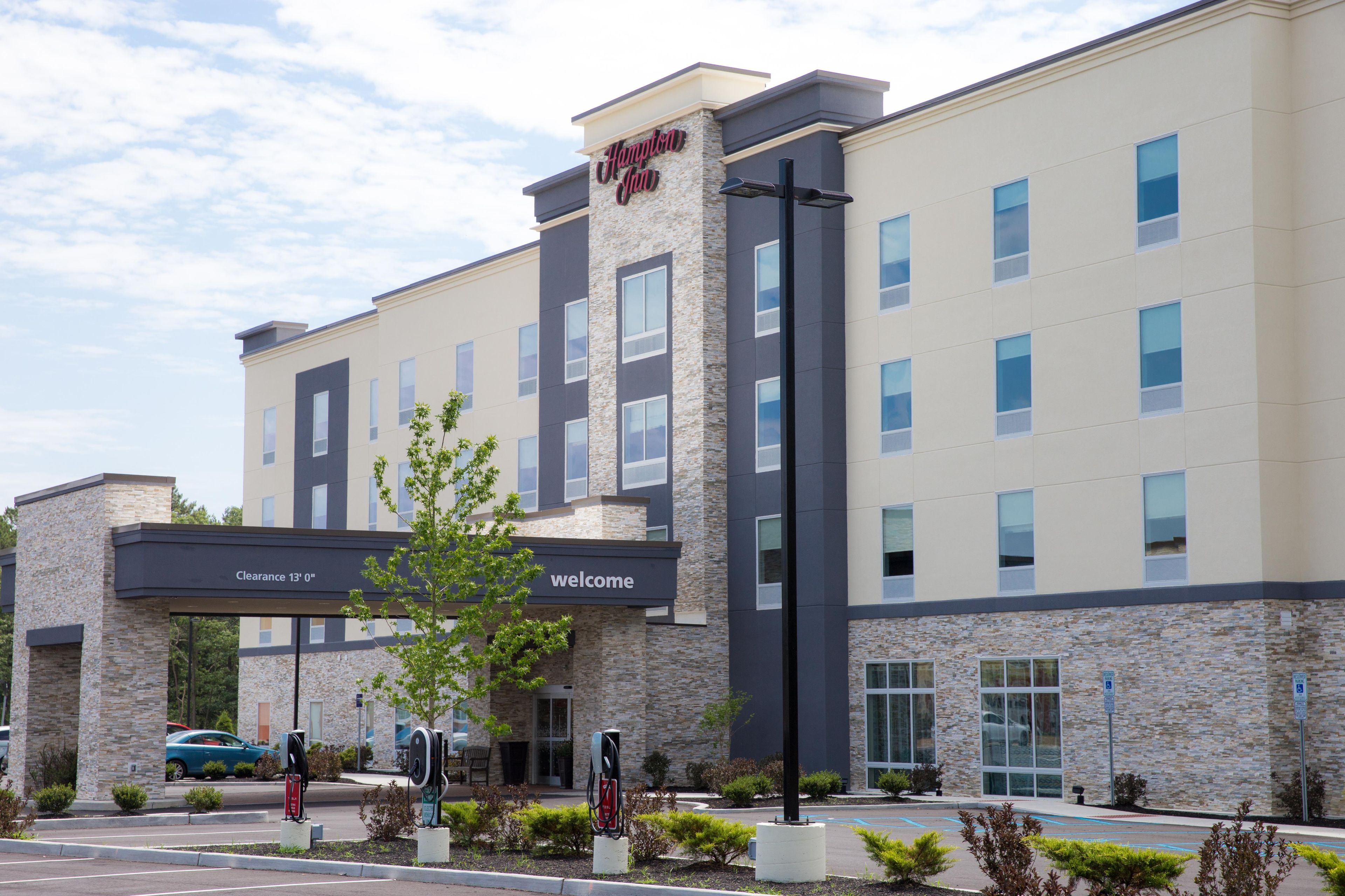 A Hampton Inn hotel with a stone facade, a clear entrance, and electric vehicle charging stations.