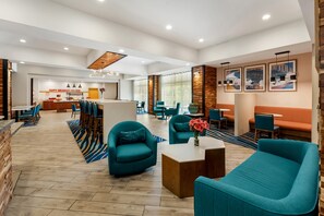Un vestíbul d'hotel modern amb zones d'estar, una recepció i obres d'art a les parets.