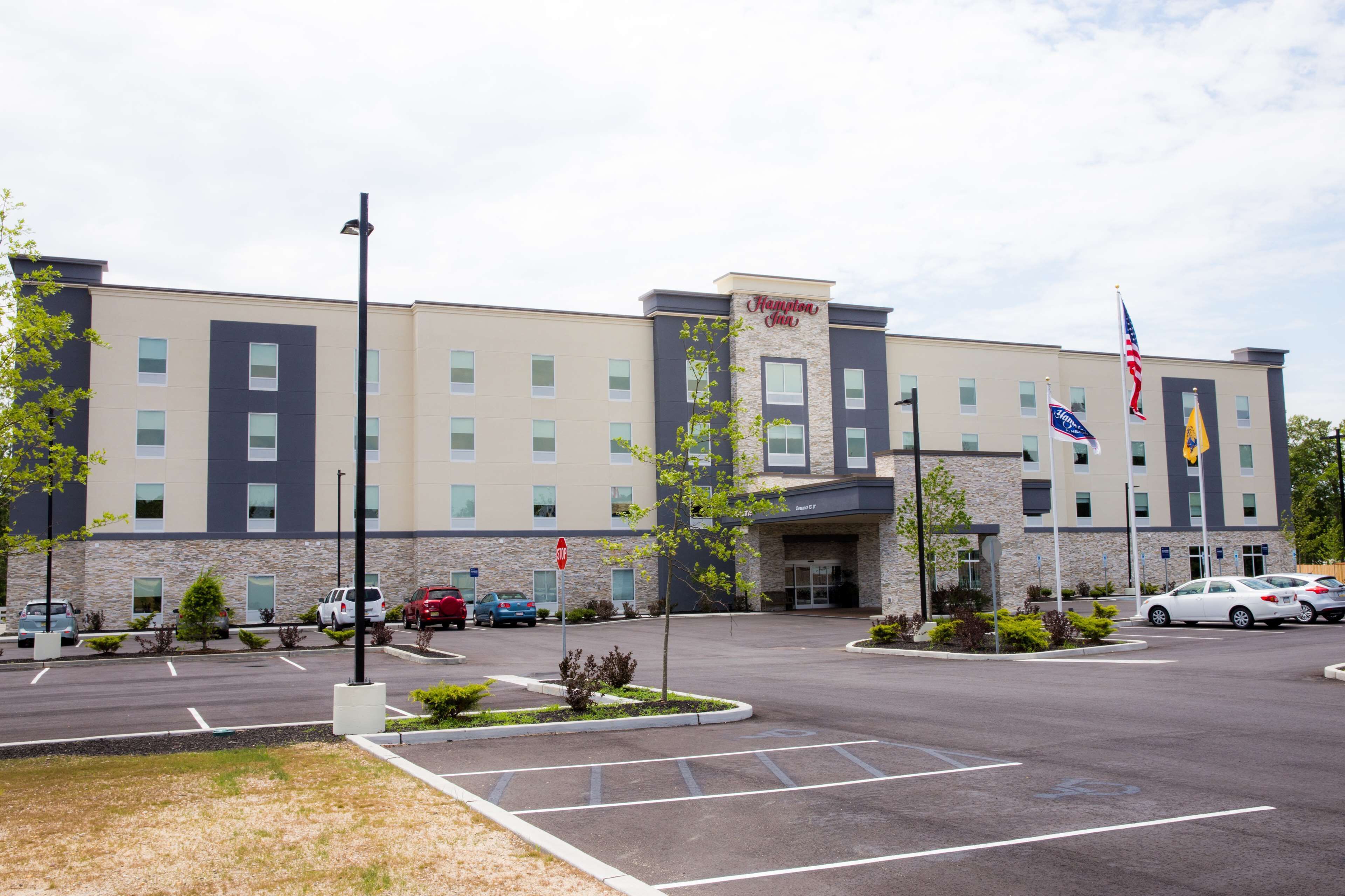 Hampton Inn -hotelli, jossa on pysäköintialue, useita lippuja ja kiviverhoiltu julkisivu.