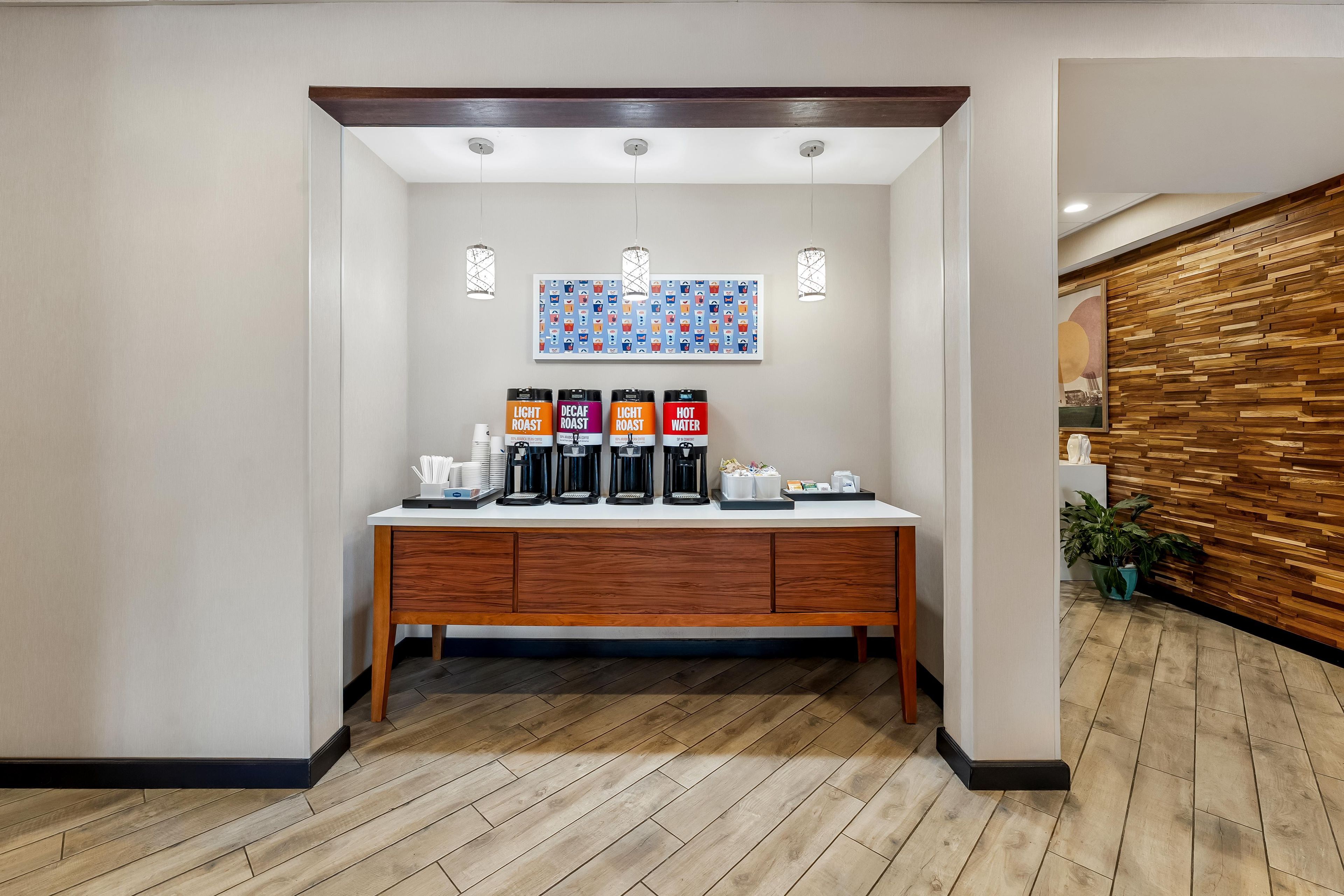 A hotel reception area with a coffee station featuring decaf, light roast, and hot water options.