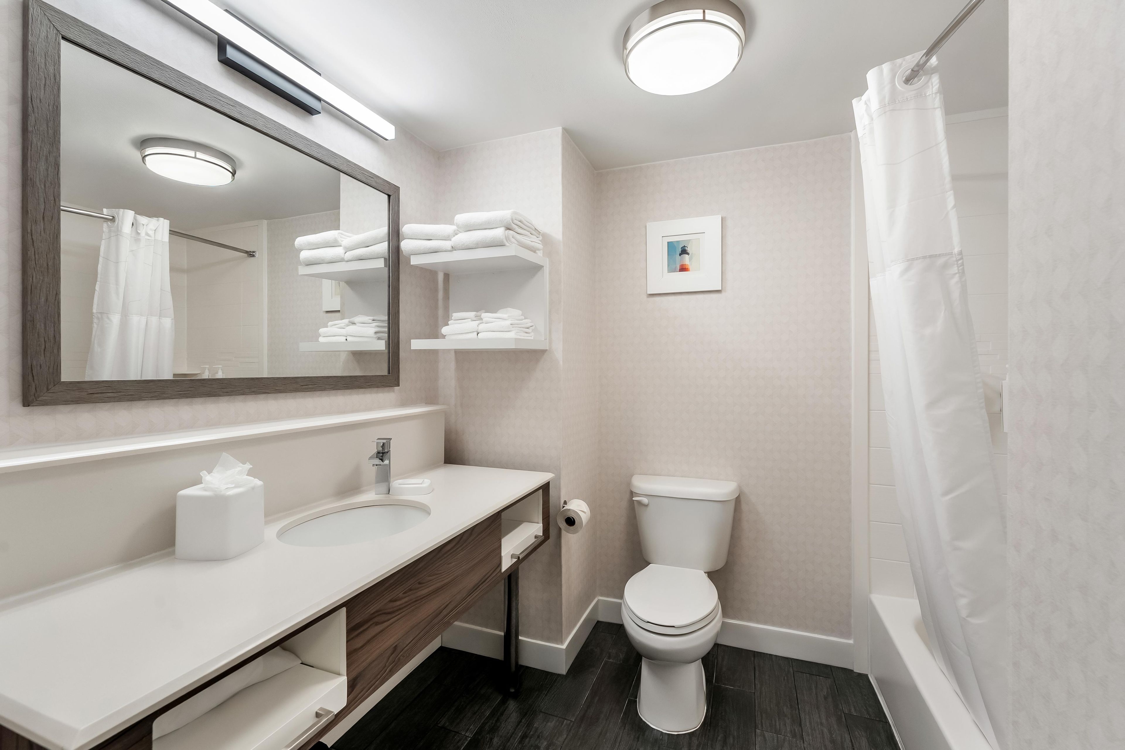 A modern bathroom with a large mirror, white sink, and a toilet.