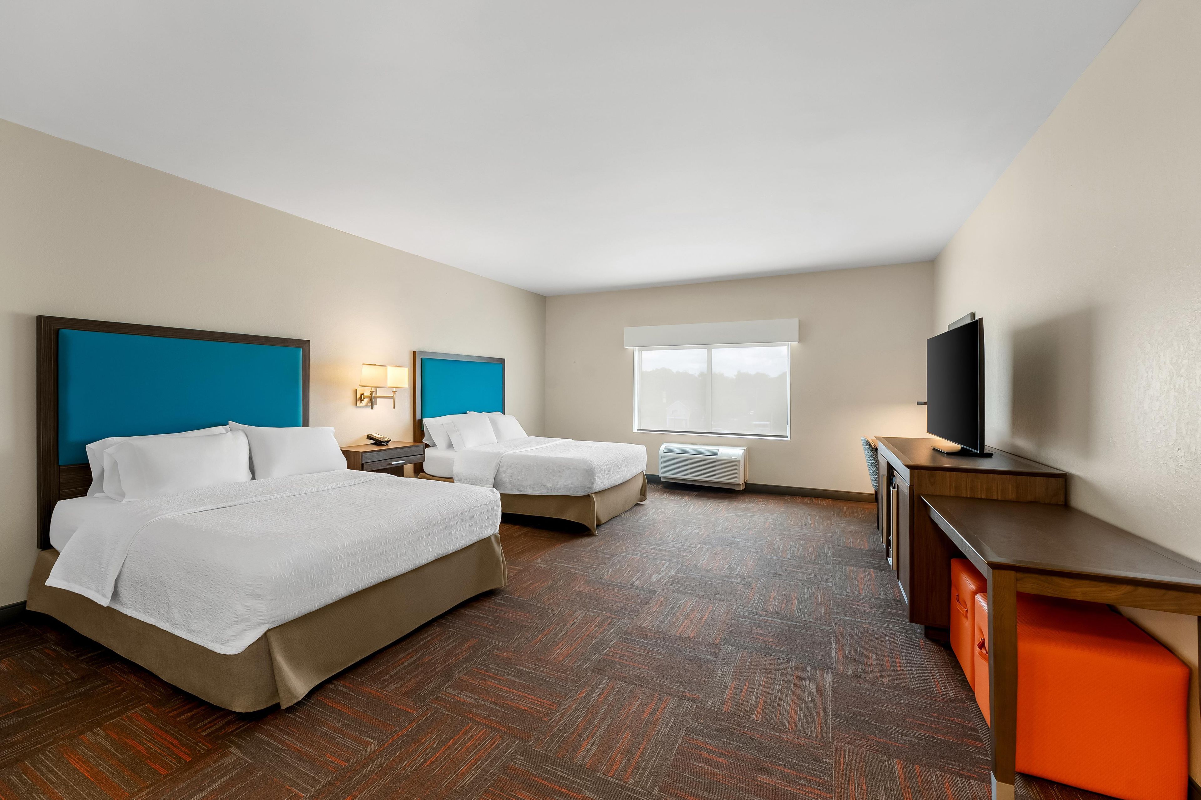 Habitación de hotel con dos camas, un escritorio, un televisor y una ventana.