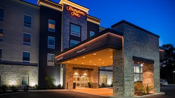 A Hampton Inn hotel with a stone facade, a clear entrance, and a neon sign.
