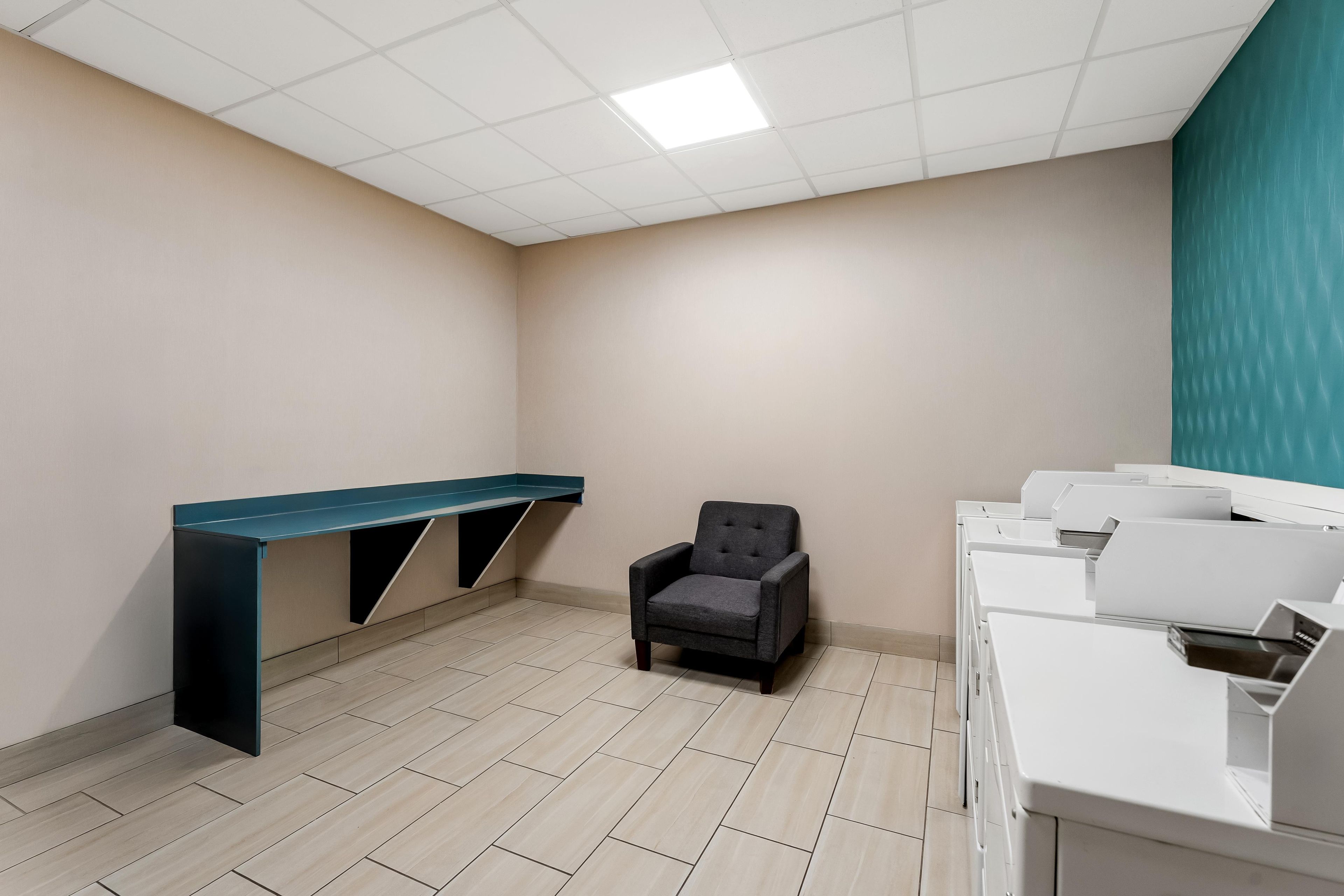 A room with a desk, a chair, and a row of white appliances.