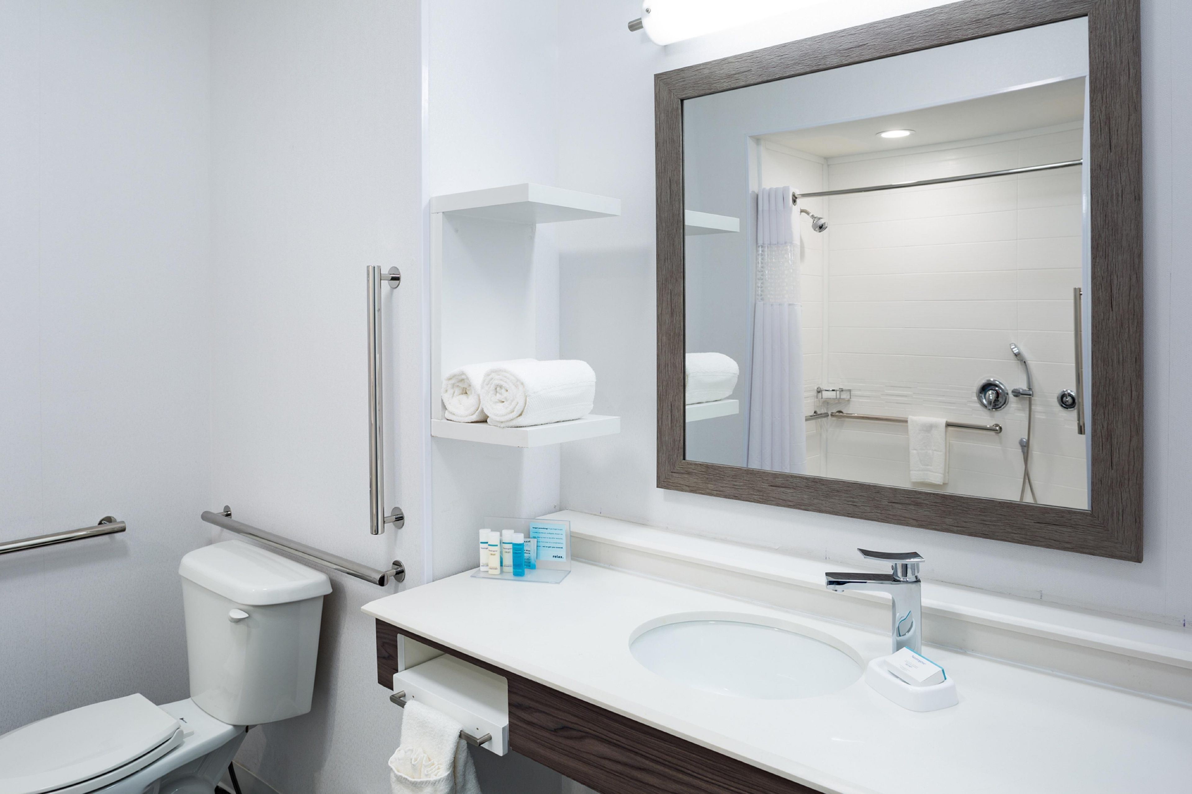 A modern bathroom with a white sink, a large mirror, a toilet, and a shower area.