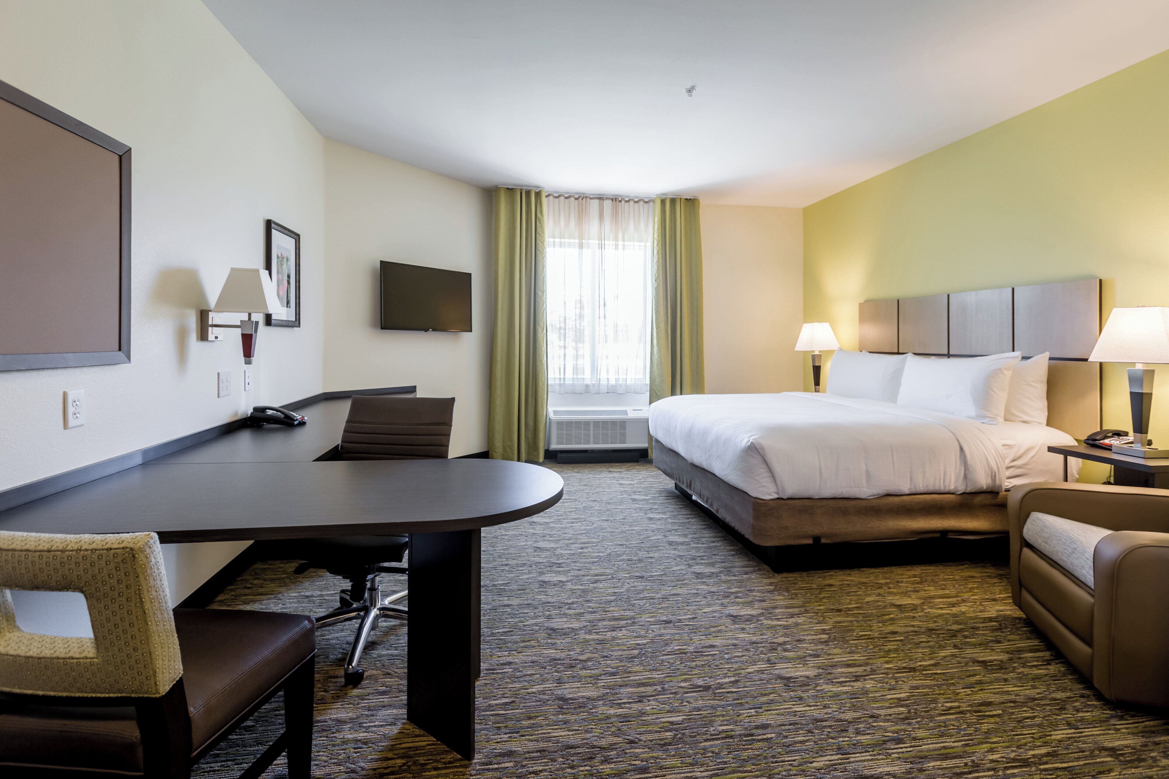A hotel room with a bed, desk, chair, and a television.
