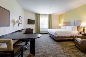 A hotel room with a bed, a desk, a chair, a TV, and a window with curtains.