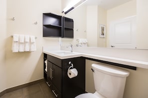 A modern bathroom with a white toilet, black cabinets, a white sink, and a mirror above the sink.