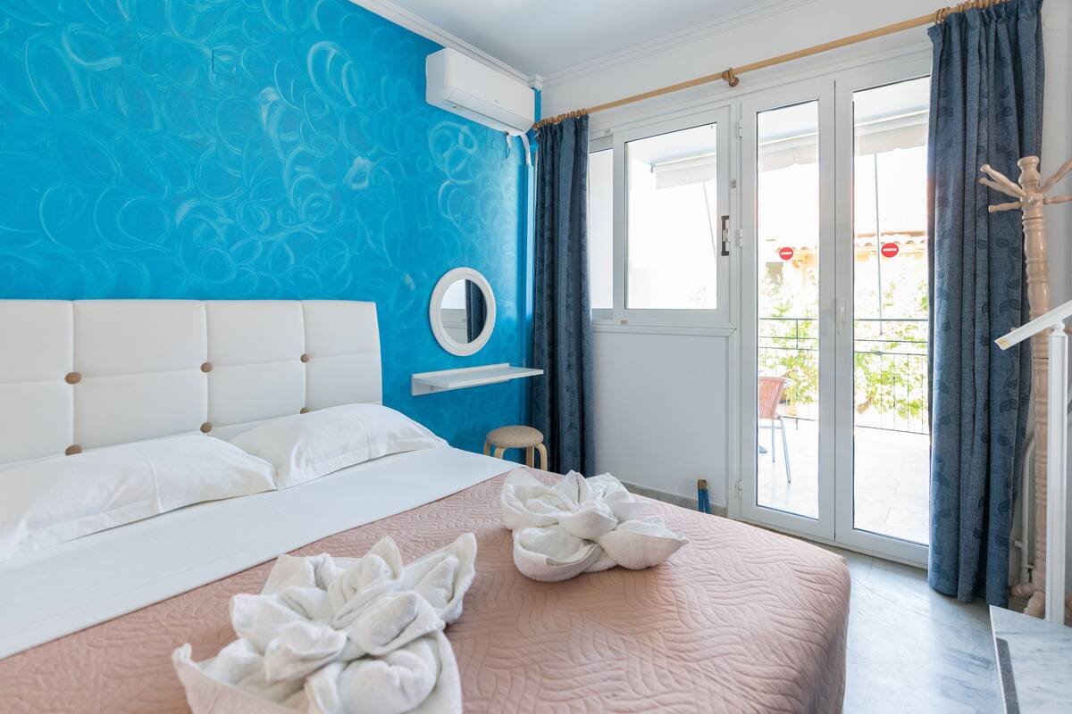 A bedroom with a bed, a round mirror, and a view of the outside through a sliding door.