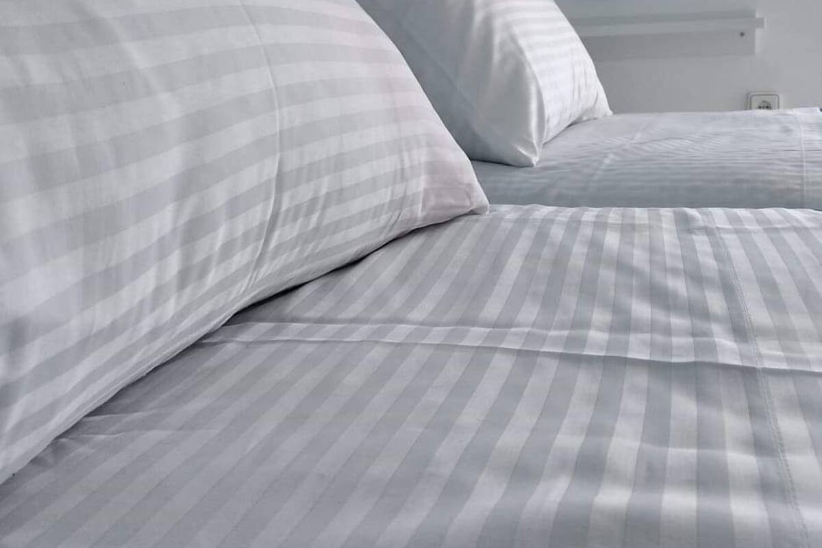 A bed with striped bedding and a round mirror on the wall.