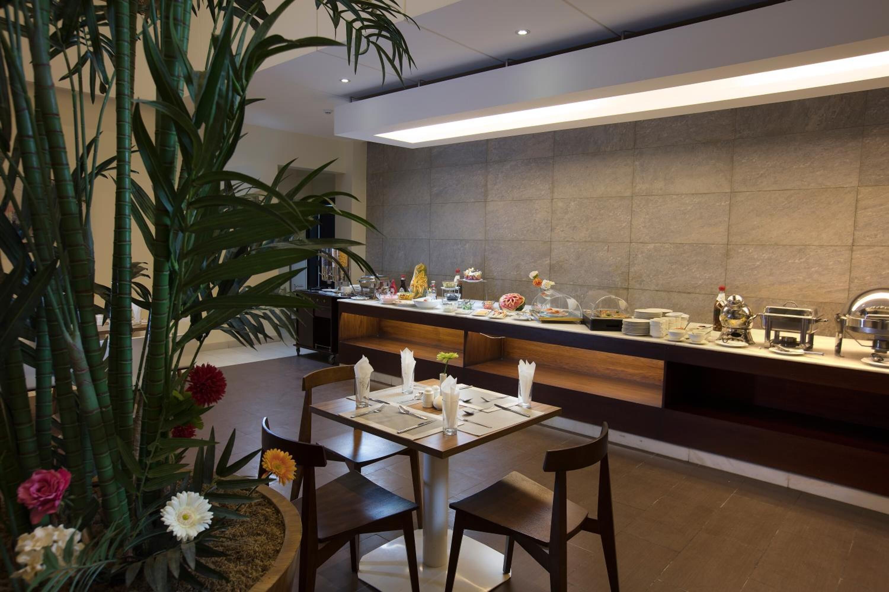 Montaje de bufé con diversos alimentos y una zona de estar con mesa y sillas.