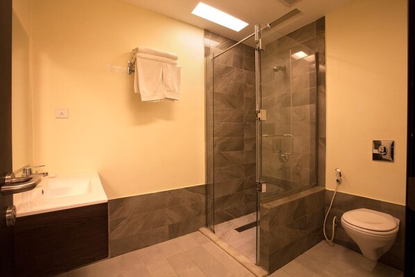 Un baño moderno con ducha envuelta en vidrio, un lavamanos y un inodoro.
