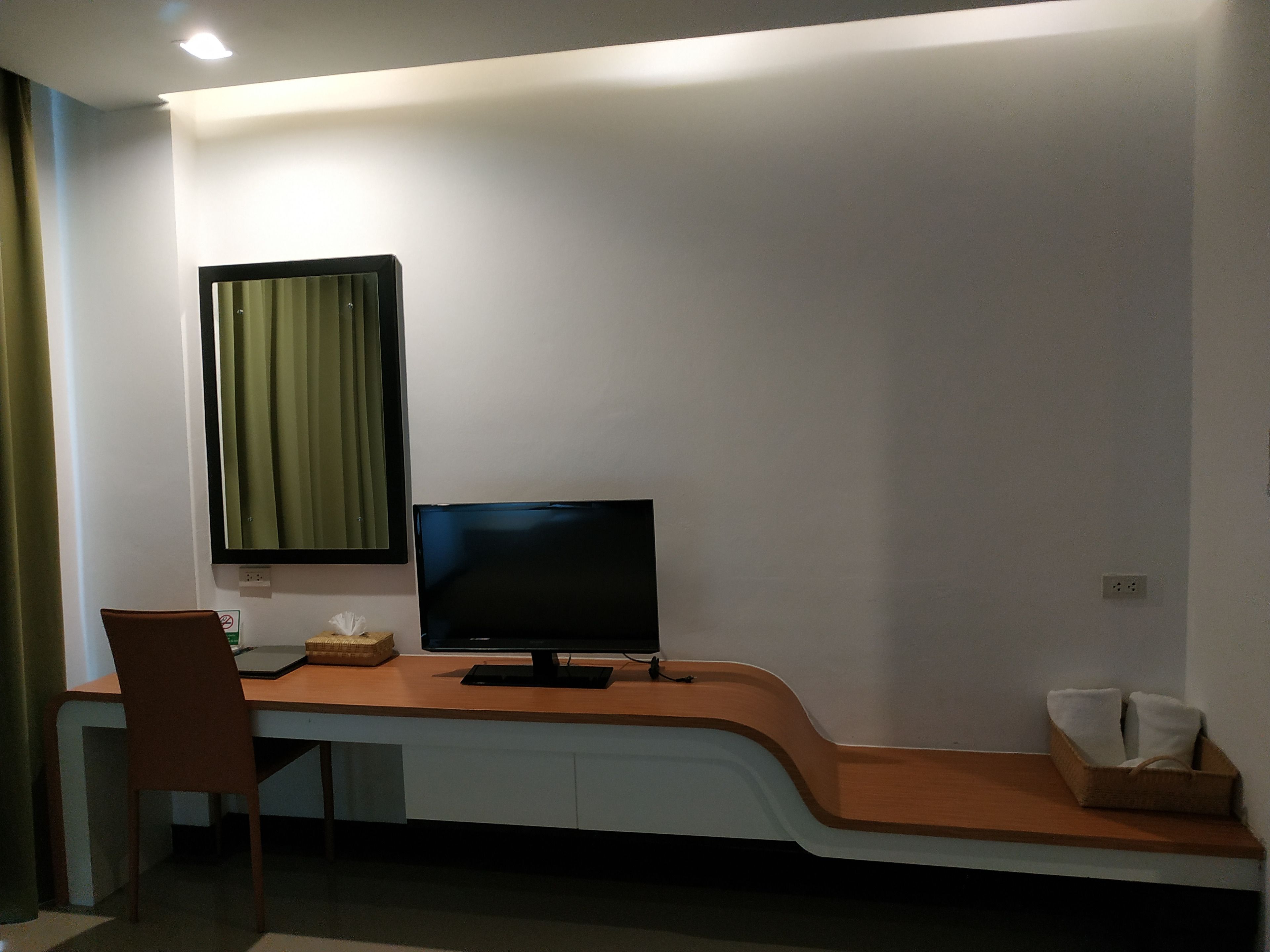 A modern hotel room with a desk, chair, and a flat-screen TV.