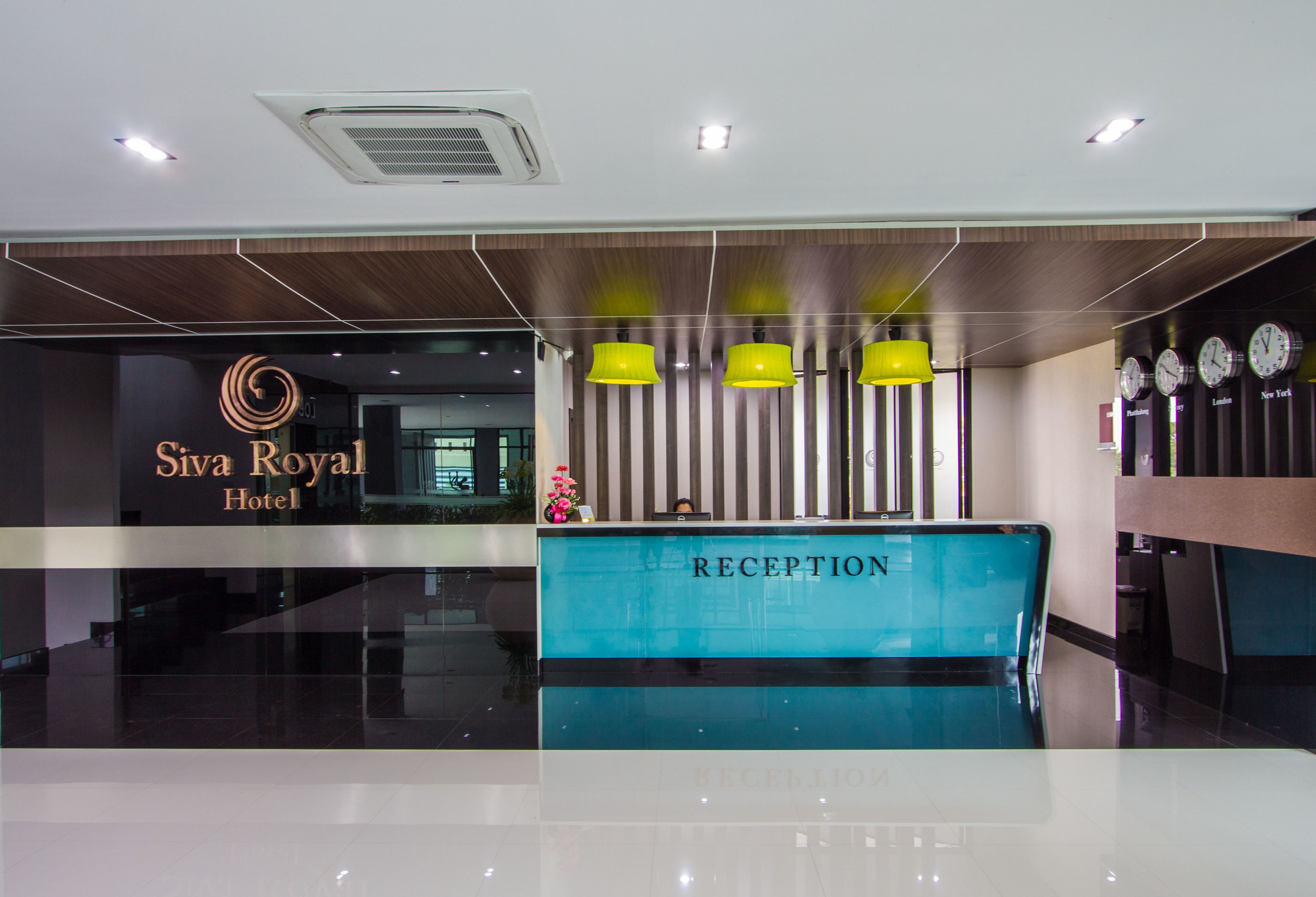 A reception desk at Siva Royal Hotel with a modern design, including a blue reception counter and yellow pendant lights.