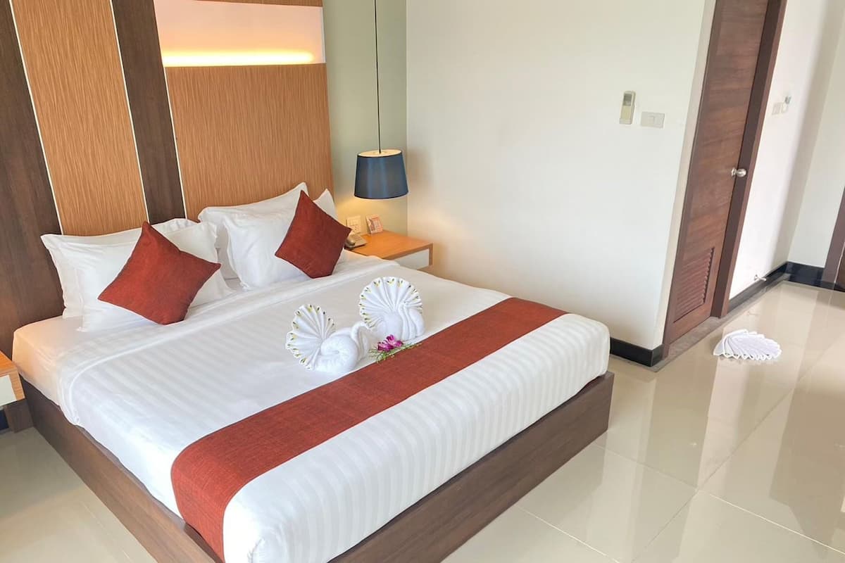 Una habitación de hotel con una cama grande, una mesita de noche con una lámpara y un cabecero de madera.