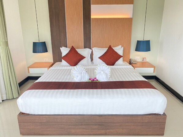 Habitación de hotel con una cama grande, dos mesitas de noche, un cabecero de madera y dos lámparas fijadas a la pared.