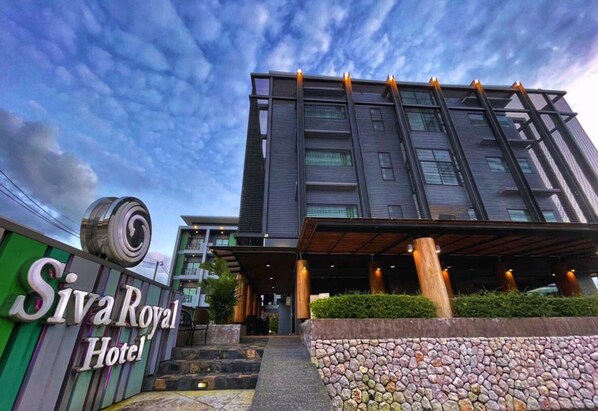 The exterior of Siva Royal Hotel with a modern architectural design, featuring a prominent entrance with steps leading up to the main building, and a signboard displaying the hotel name. - Siva Royal Hotel (Phatthalung)
