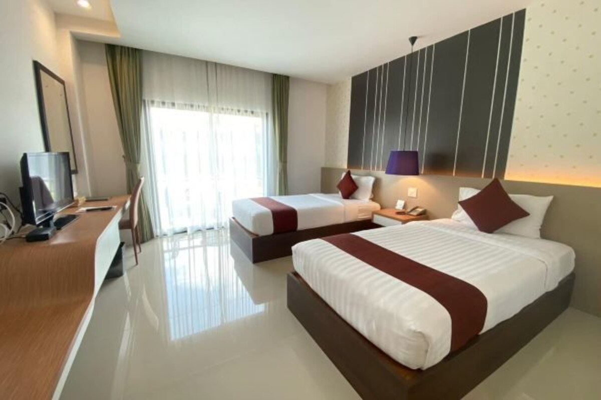 A hotel room with a large bed, a smaller bed, a desk, and a TV.