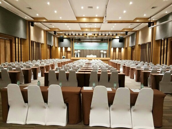 A conference room with rows of tables and chairs, equipped with microphones and speakers, suitable for meetings or presentations.