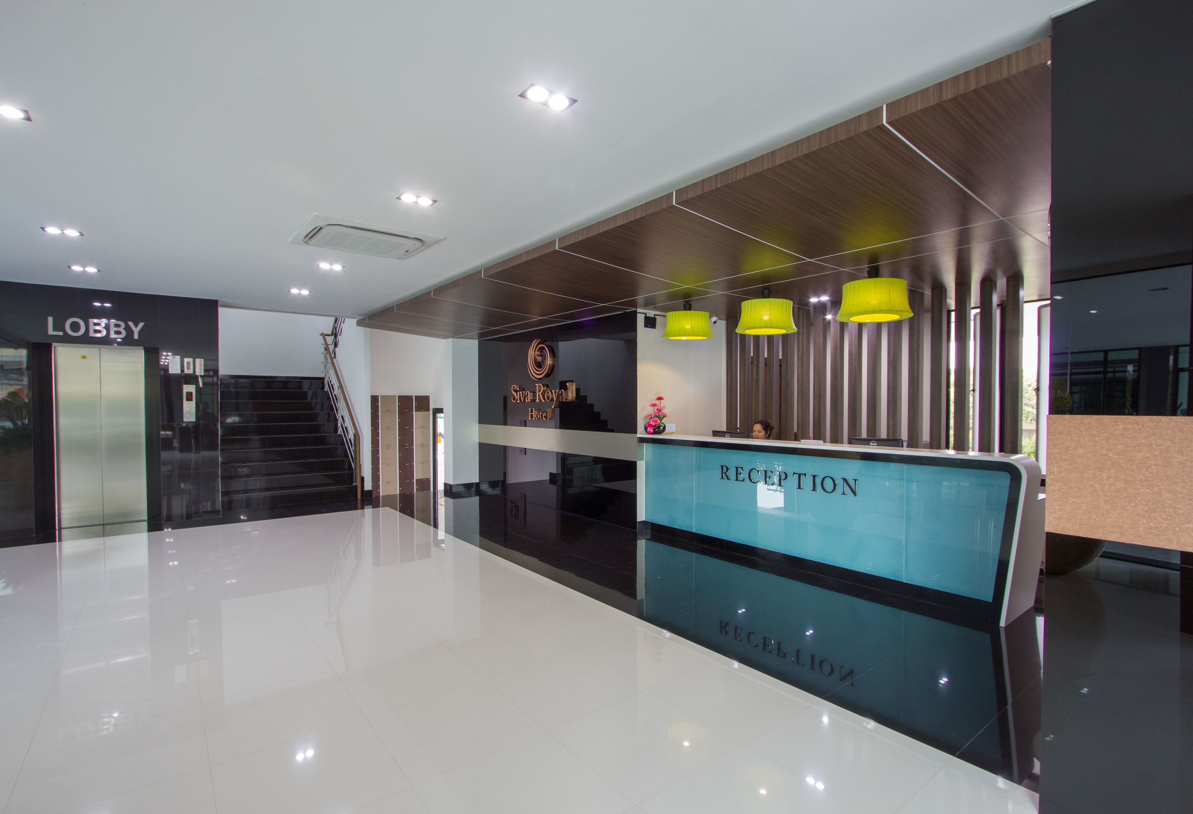 A hotel lobby with a reception desk, a lobby area, and a staircase leading to the upper floors.