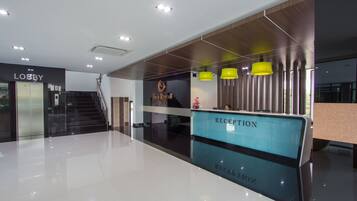 A hotel lobby with a reception desk, a lobby area, and a staircase leading to the upper floors.