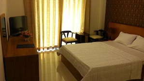 Une chambre d’hôtel avec un lit, un bureau avec un ordinateur, une chaise et une petite table.