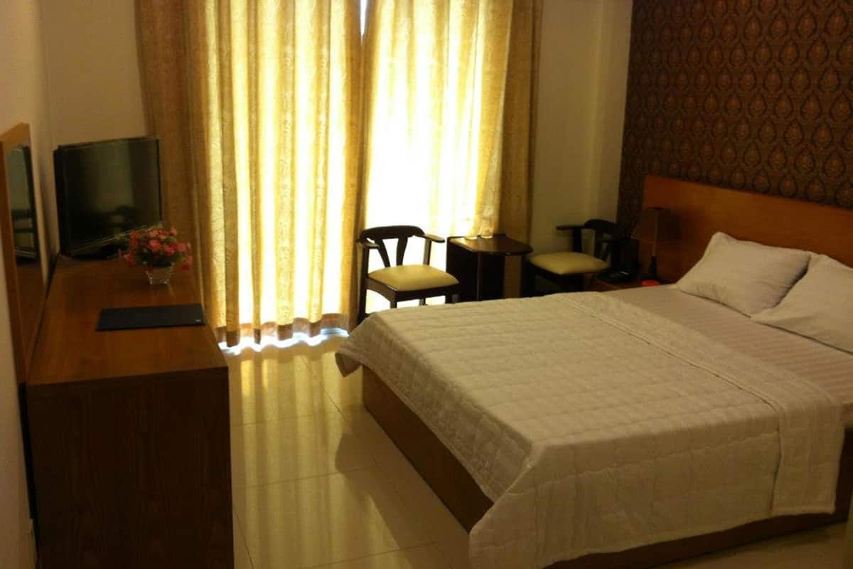 Ein Hotelzimmer mit Bett, Schreibtisch mit Computer, Stuhl und kleinem Tisch.