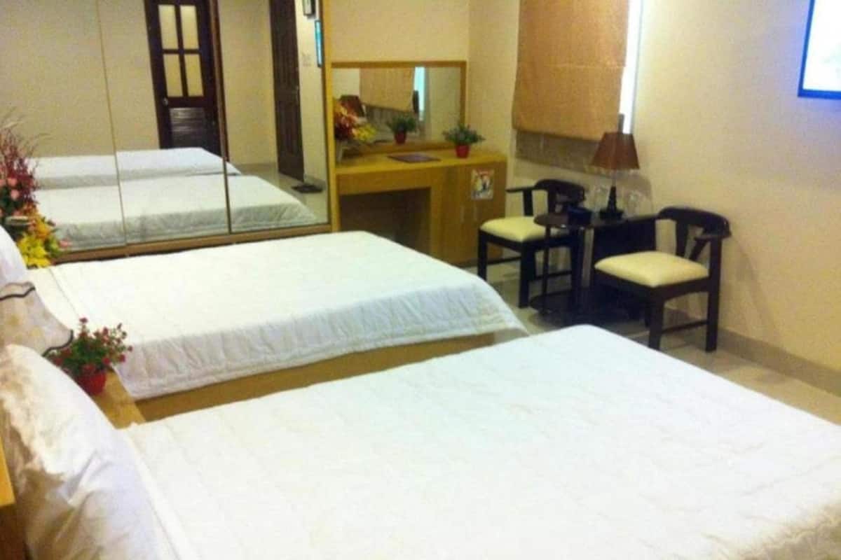 Ein Hotelzimmer mit zwei Betten, einem Schreibtisch, einem Stuhl, einem Spiegel und einem Fenster mit Vorhang.
