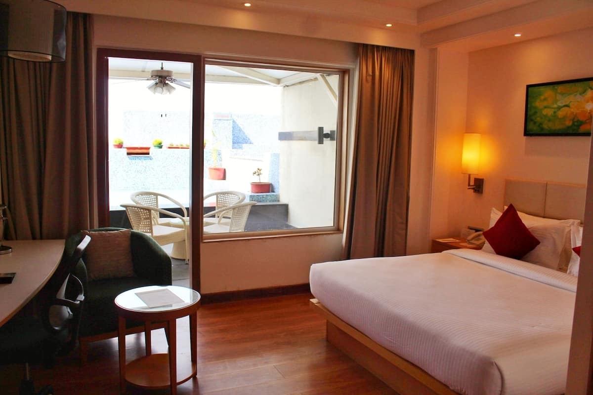 A hotel room with a bed, a desk, a chair, a window, and a view of the outside.