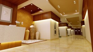 Un lobby moderno de hotel con una recepción, jarrones decorativos y un suelo de mármol.