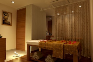 A spa room with a massage table, candles, and a wooden panel wall.