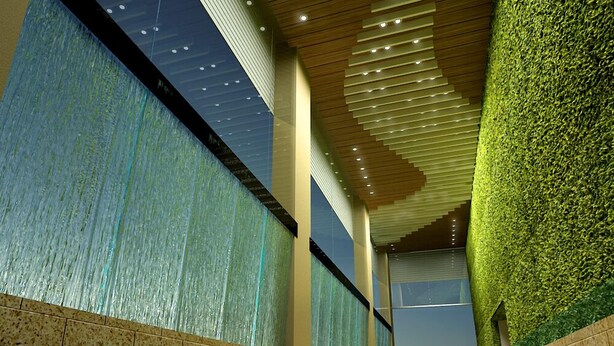Un pasillo con piso de baldosas, techo de madera con iluminación empotrada y paredes cubiertas de follaje verde.