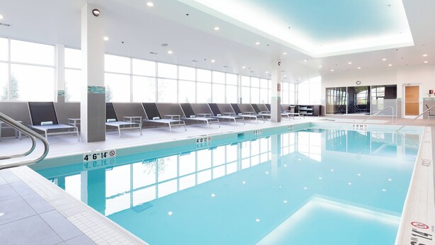 Una piscina interior con agua cristalina, tumbonas y un diseño moderno de techo.