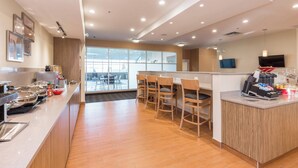 Una cocina moderna con una encimera larga, sillas de madera y un televisor montado en la pared.