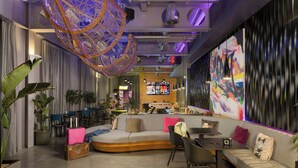 A modern lounge area with a curved sofa, a dining table, and a large abstract painting on the wall.