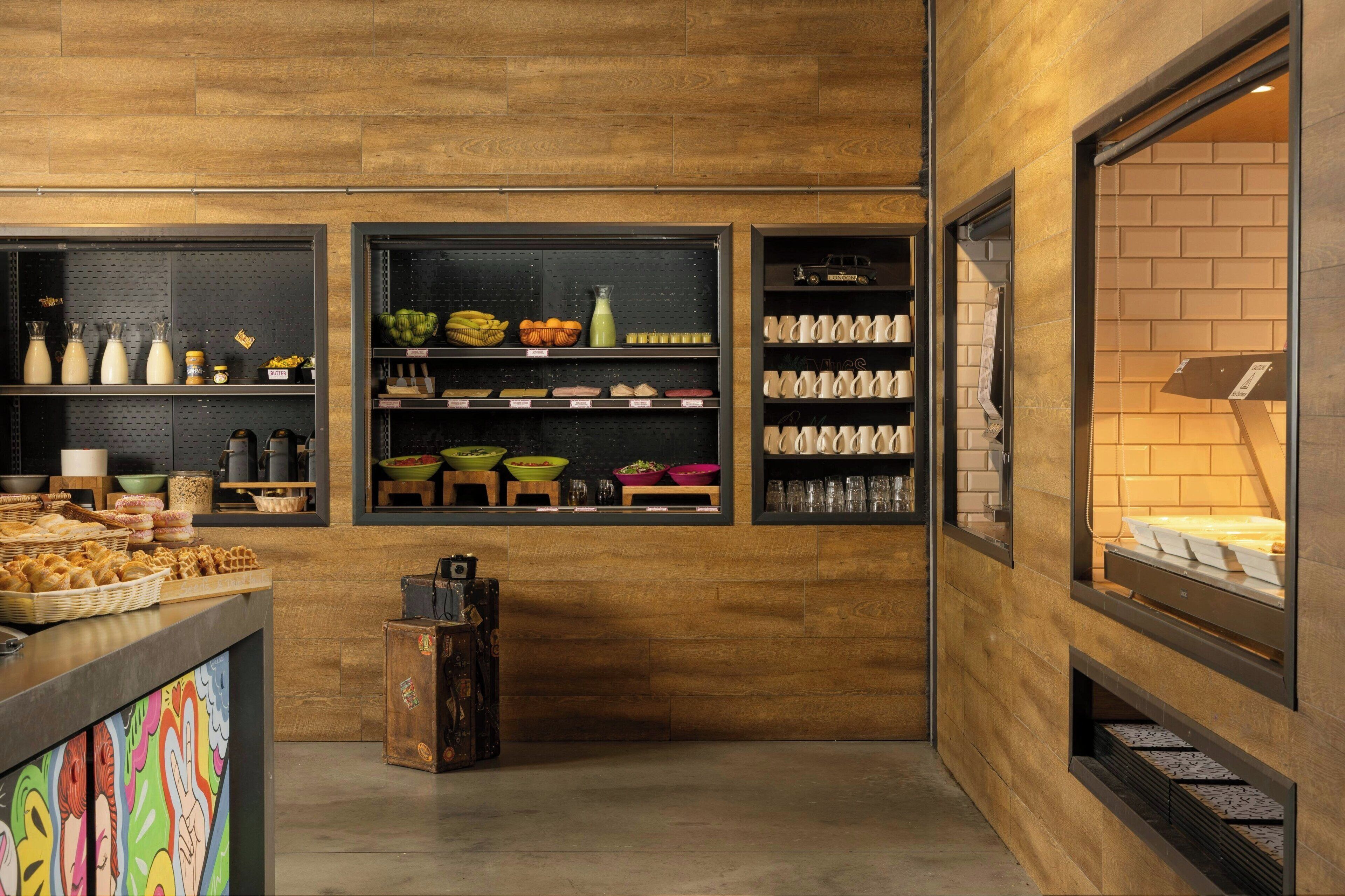 Une boulangerie avec des étagères remplies de produits de boulangerie, un présentoir de pâtisseries et un coin café.