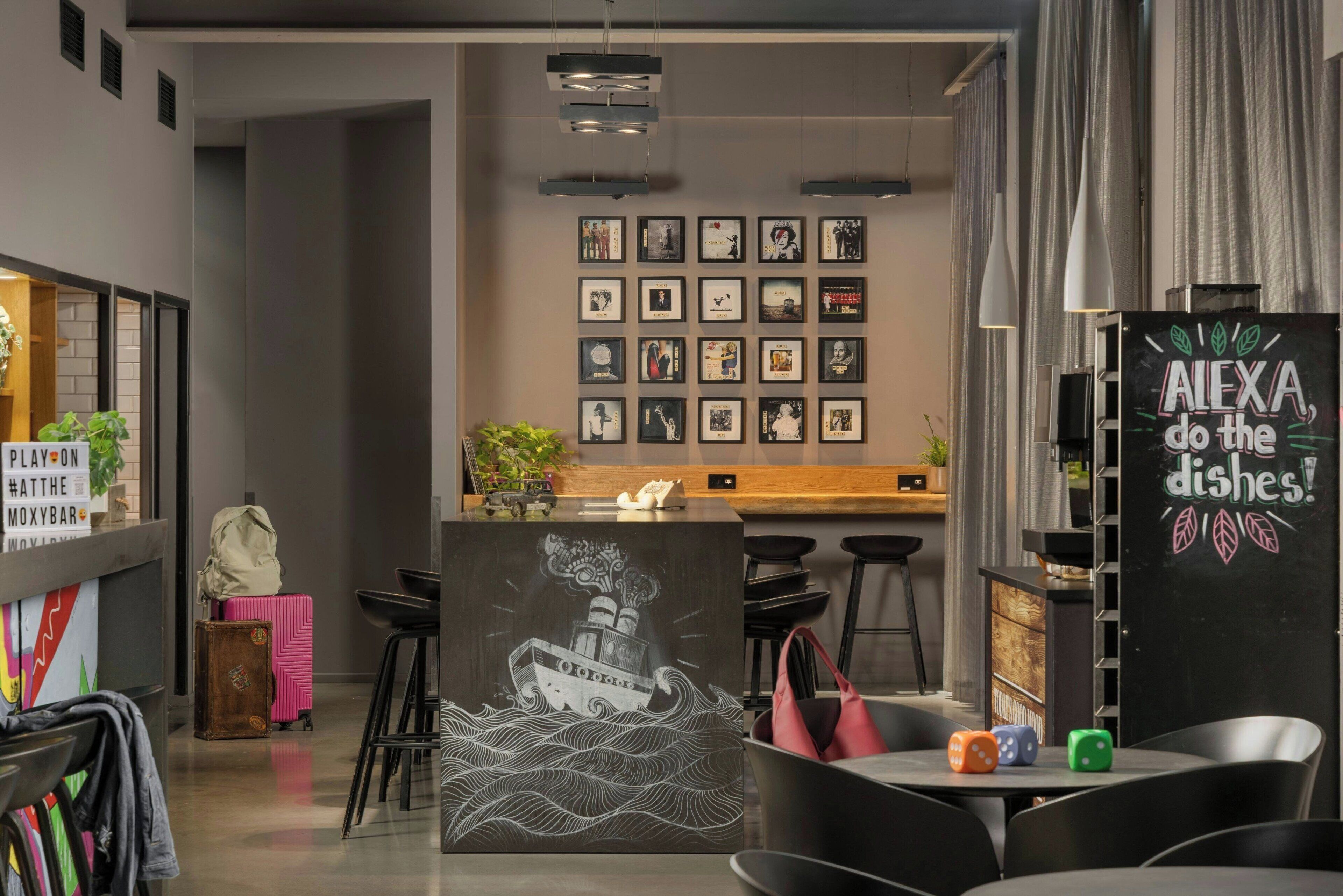 Un interno di ristorante moderno con zona bar, quadri alle pareti e una lavagna.